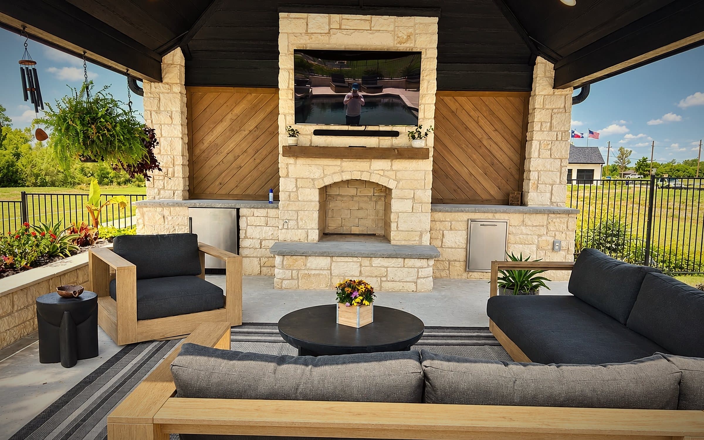 Covered patio with a limestone fireplace, mounted TV and outdoor seating